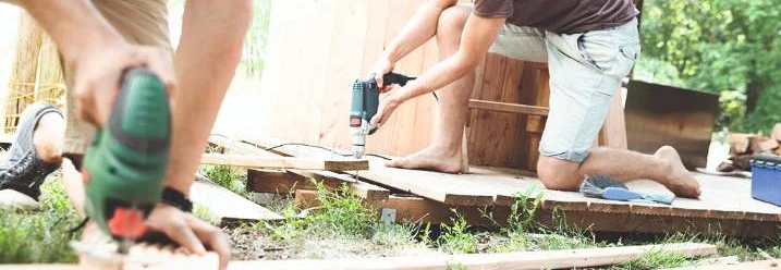 Zwei Personen bauen ein Holzdeck mit Akkuschrauber